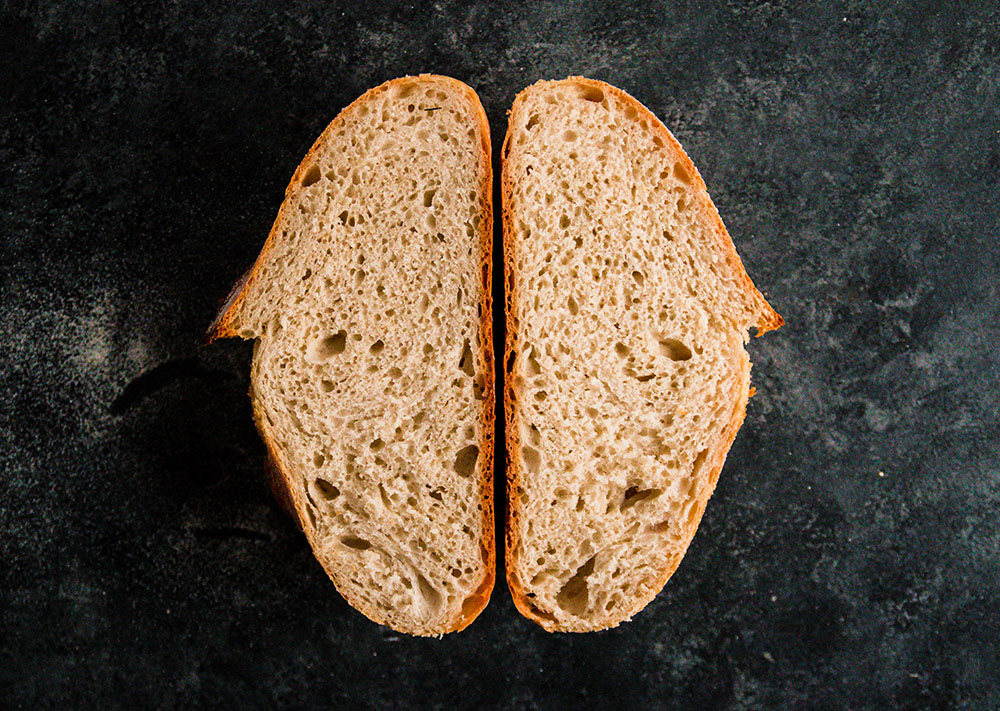 Two halves of a loaf of bread, facing upwards to show the interior crumb.