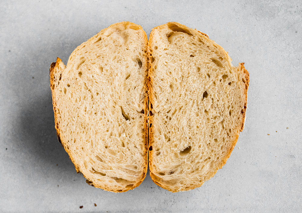 loaf of bread, sliced in half, sitting on a white table.